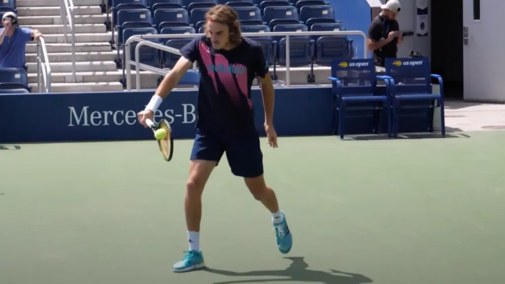 A player hitting a one-handed backhand with full arm extension and balanced body position